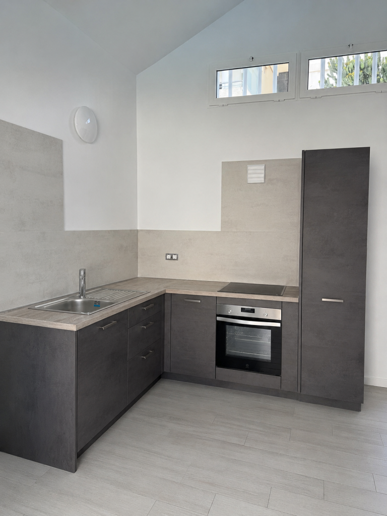 Cocina con mobiliario gris y horno integrado