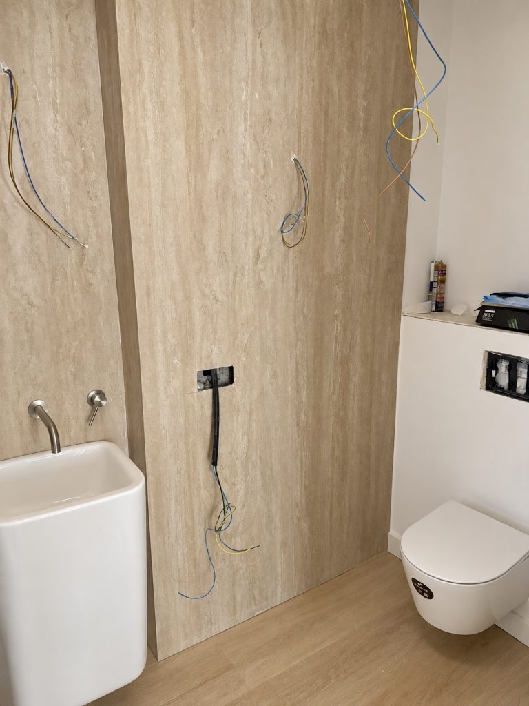 Baño con ducha revestida en efecto madera, bañera blanca e inodoro suspendido