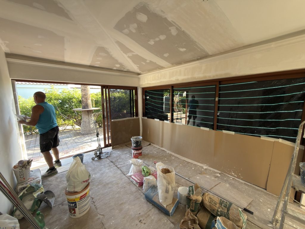 Interior en obras con techo de placas, paredes abiertas y materiales de construcción