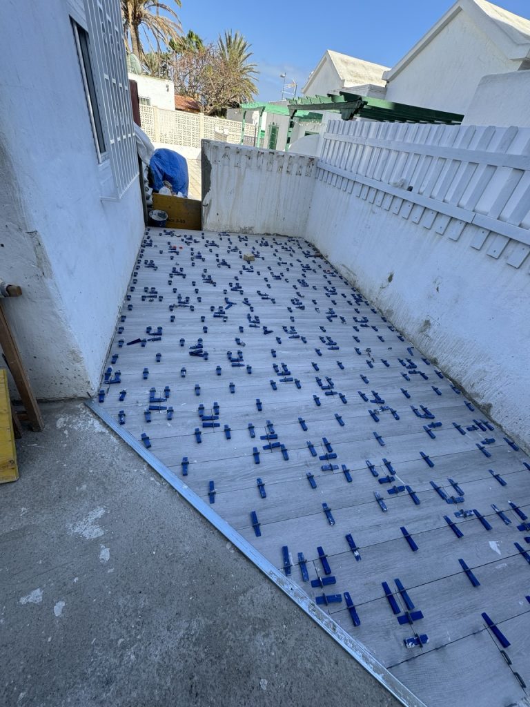 Pasillo exterior con baldosas y niveladores durante la colocación del pavimento