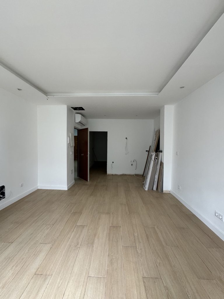 Vista de una estancia con suelo de efecto madera, paredes blancas y techo acabado
