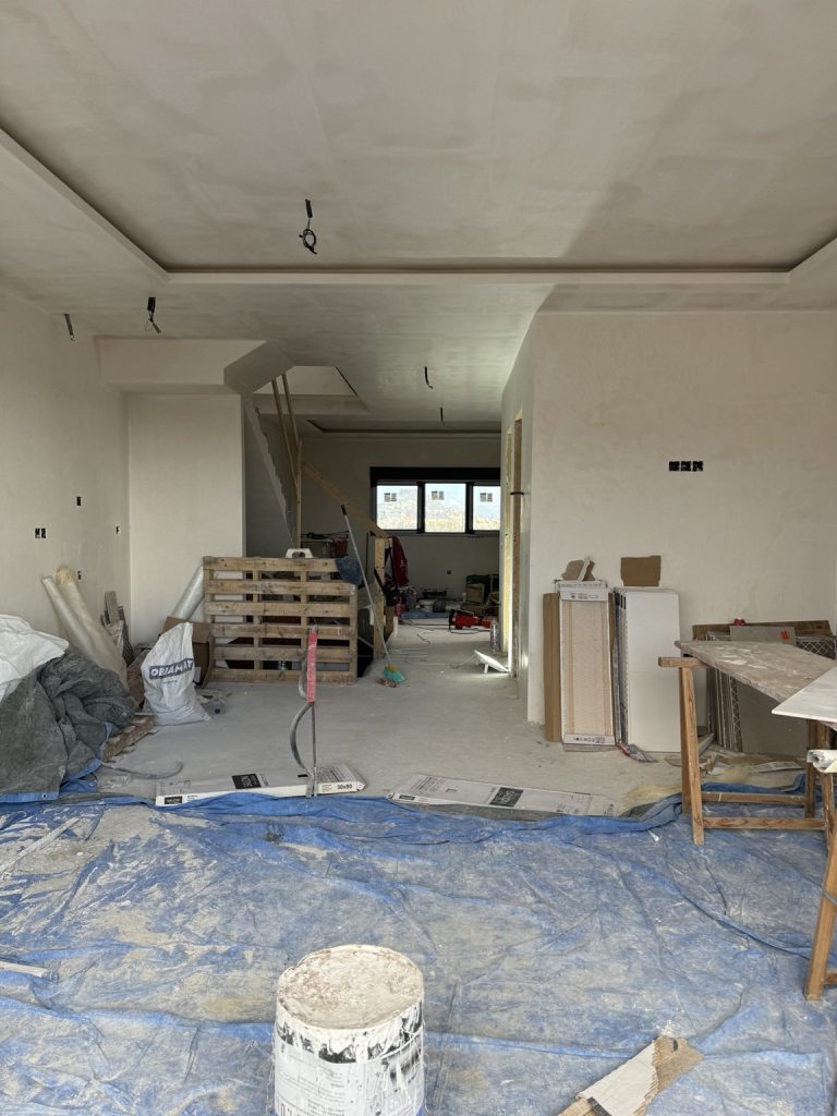 Estancia en obras con materiales, suelo protegido y techo en preparación