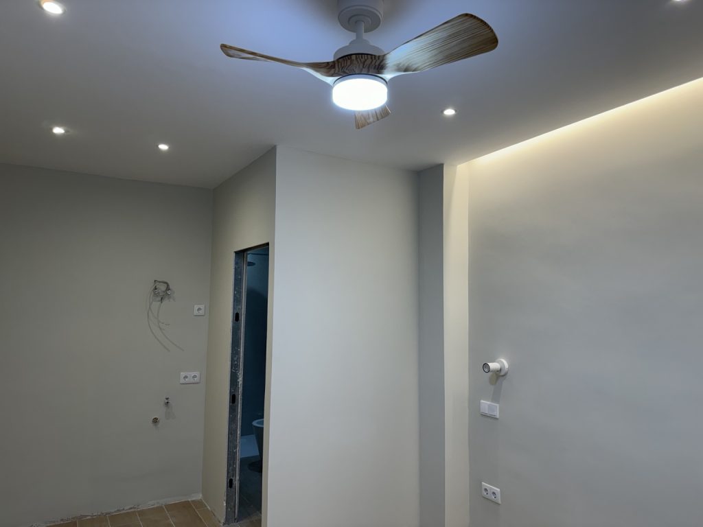 Interior con iluminación perimetral, focos empotrados y ventilador de techo