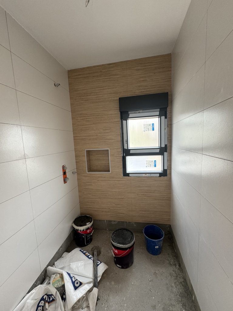 Baño en obras con ventana, hornacina y revestimiento de efecto madera