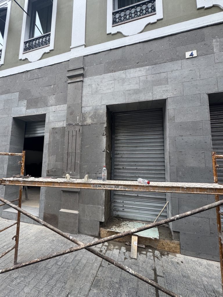 Fachada con nuevo revestimiento gris y huecos de acceso, con andamio todavía instalado